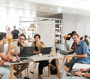 People with notebooks sitting around a table talking .